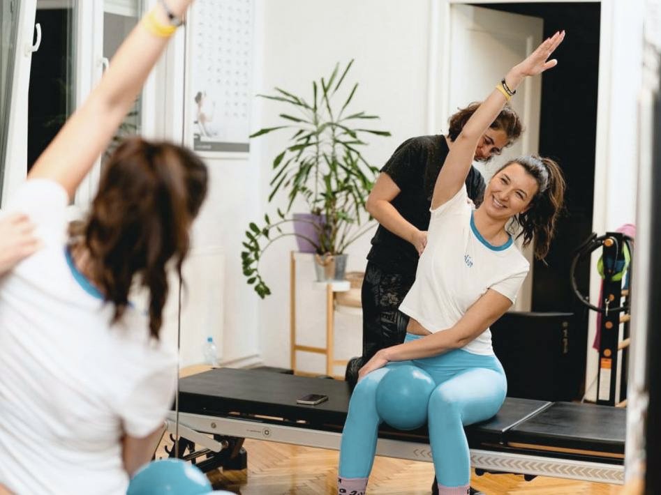 Marina guiding a client through a side stretch in the bright MATPilates studio